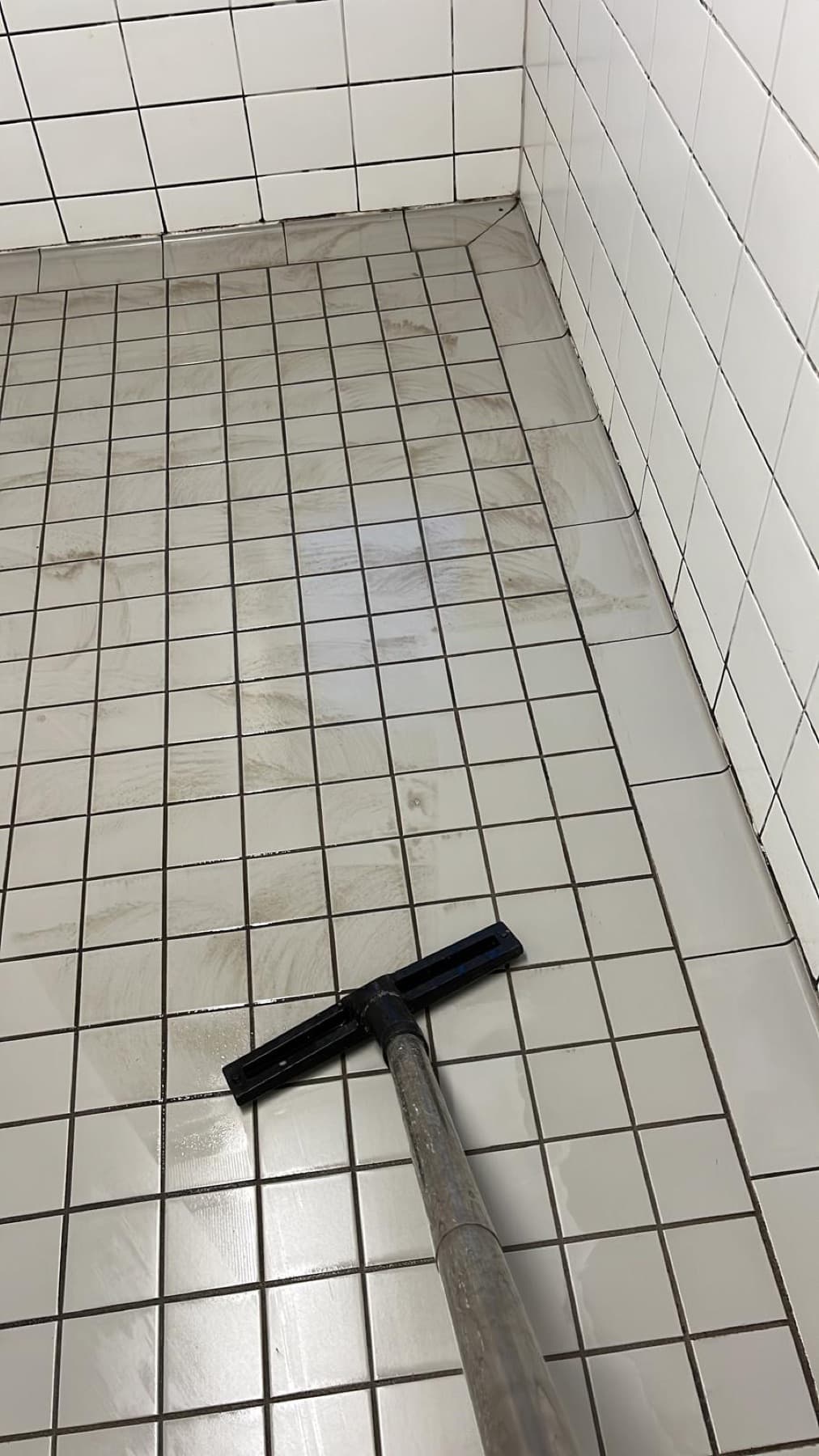 Abzieher auf frisch gereinigtem Fliesenboden in einem Sanitärbereich