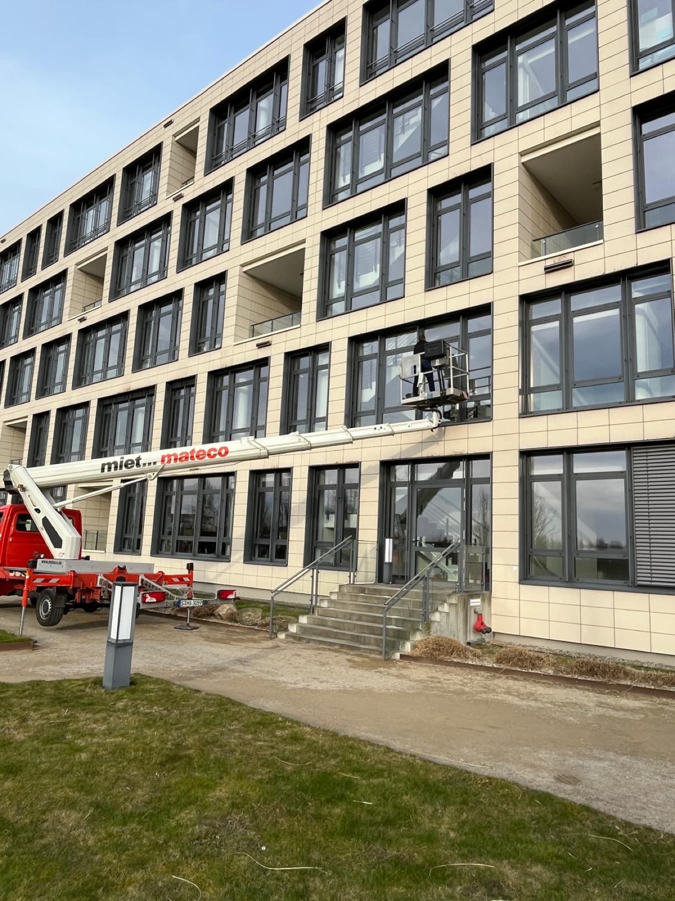 Hebebühne vor einem mehrgeschossigen Bürogebäude bei der Fassadenreinigung