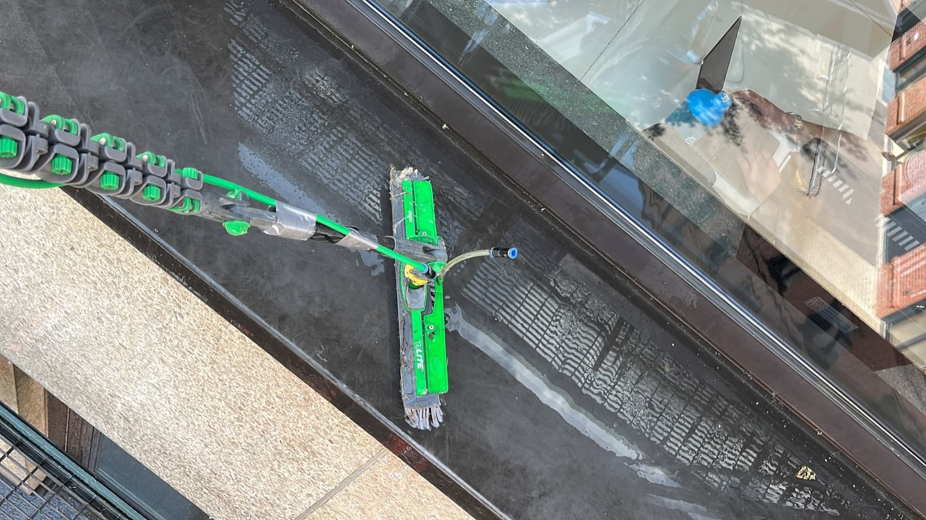 Wischer mit entmineralisiertem Wasser zieht eine Fensterscheibe streifenfrei ab